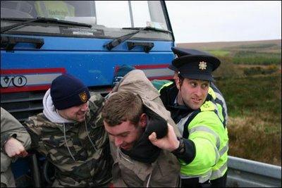 A Garda physically removes protesters from a road