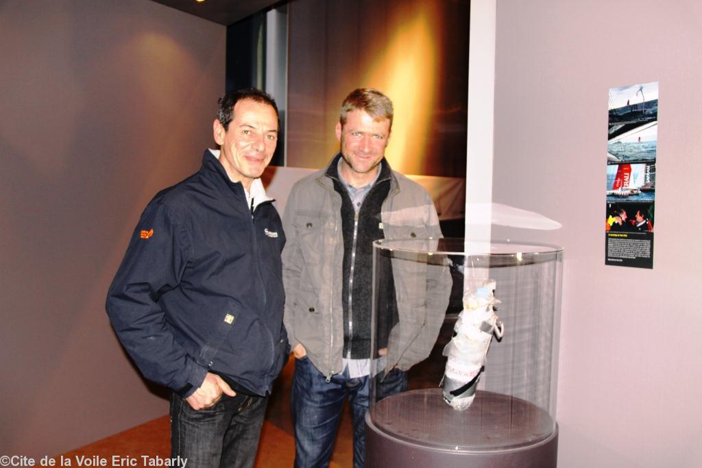 Marc Guillemot et Yann Eliès dans le Cabinet de curiosité de l'exposition devant la fameuse bouteille de survie (composée d'une boîte de pâté Henaff  d'un morceau de pain et d'un couteau et de comprimés de morphine) confectionnée et lancée par Marc Gu