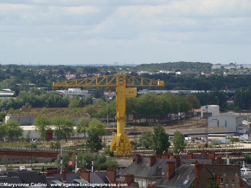 La grue Titan jaune vue de la tour du Musée Dobrée à Nantes. Éoliennes et pilônes haute tension dans le lointain.