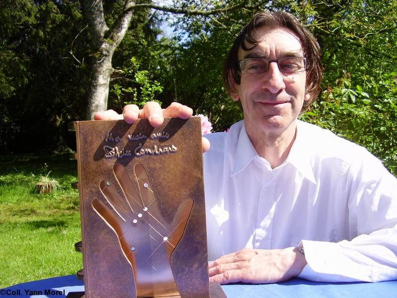 Yann Morel pose avec la sculpture symbolique du prix Blaise Cendrars représentant la main du poète et la constellation d'Orion. (Coll. personnelle du poète).