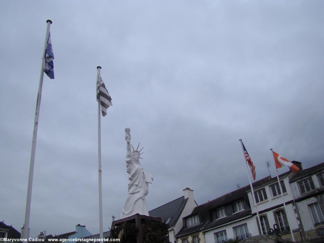 Gourin. La réplique de la statue de la Liberté de New York de Bartholdi rappelle l'émigration massive des Bretons du Kreizh Breizh aux Amériques. Entourée des drapeaux du Québec à droite et de Québec ville à gauche. Le manque de vent masquait ses fleurs de lys blanches sur fond bleu et la croix blanche.