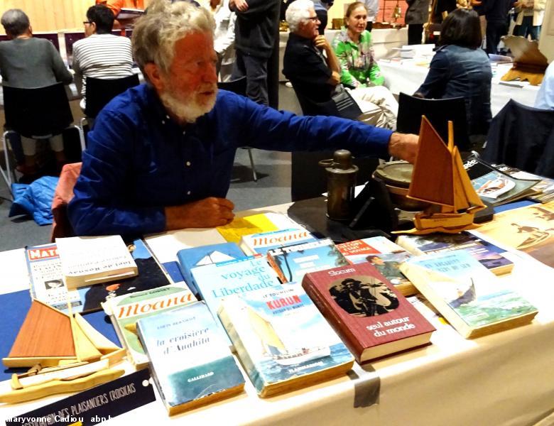 23- M. Marcellin, de l'association Les Amis du Kurun, tient le stand avec des livres de récits de voyages maritimes prêtés par des adhérents pour le salon.