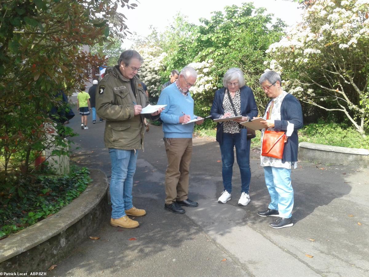 Citoyens en train de signer la pétition à la sortie d'un bureau de vote.